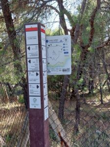 A close up of a recycled plastic pole with directional signs and a Poros cycling trails trailhead