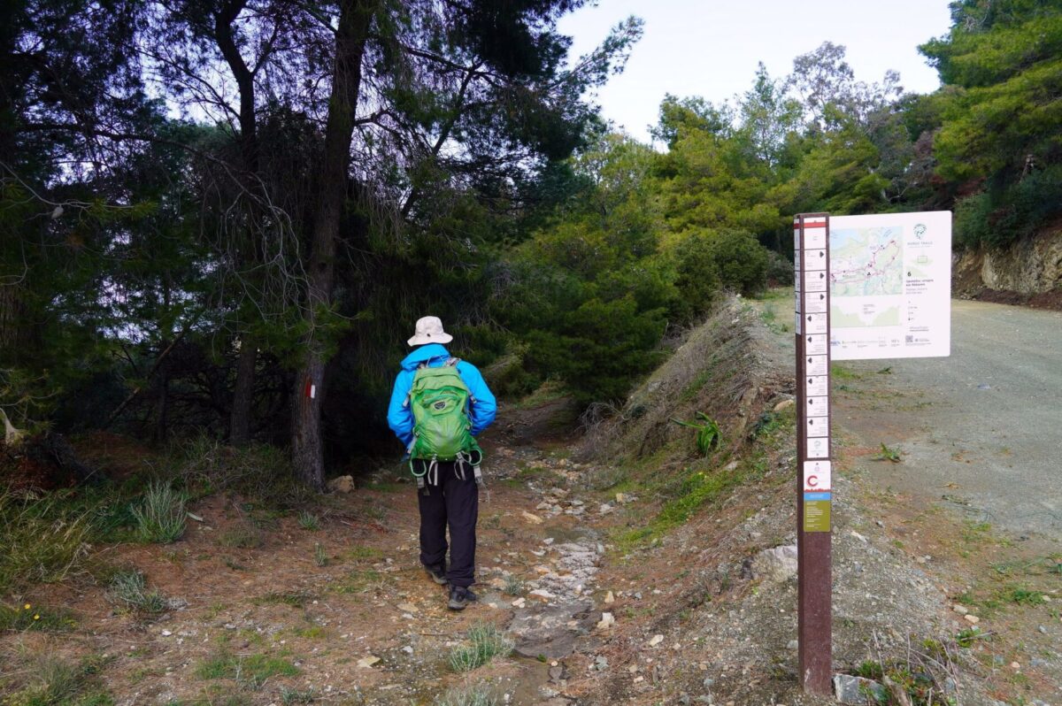 A hiker on Poros trails and a trailhead sign