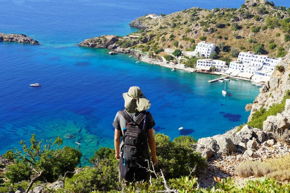 A hiker looking towards the sea and a Greek coastal village in Crete A hiker looking at the sea and Loutro coastal village in Sfakia, Crete, Greece
