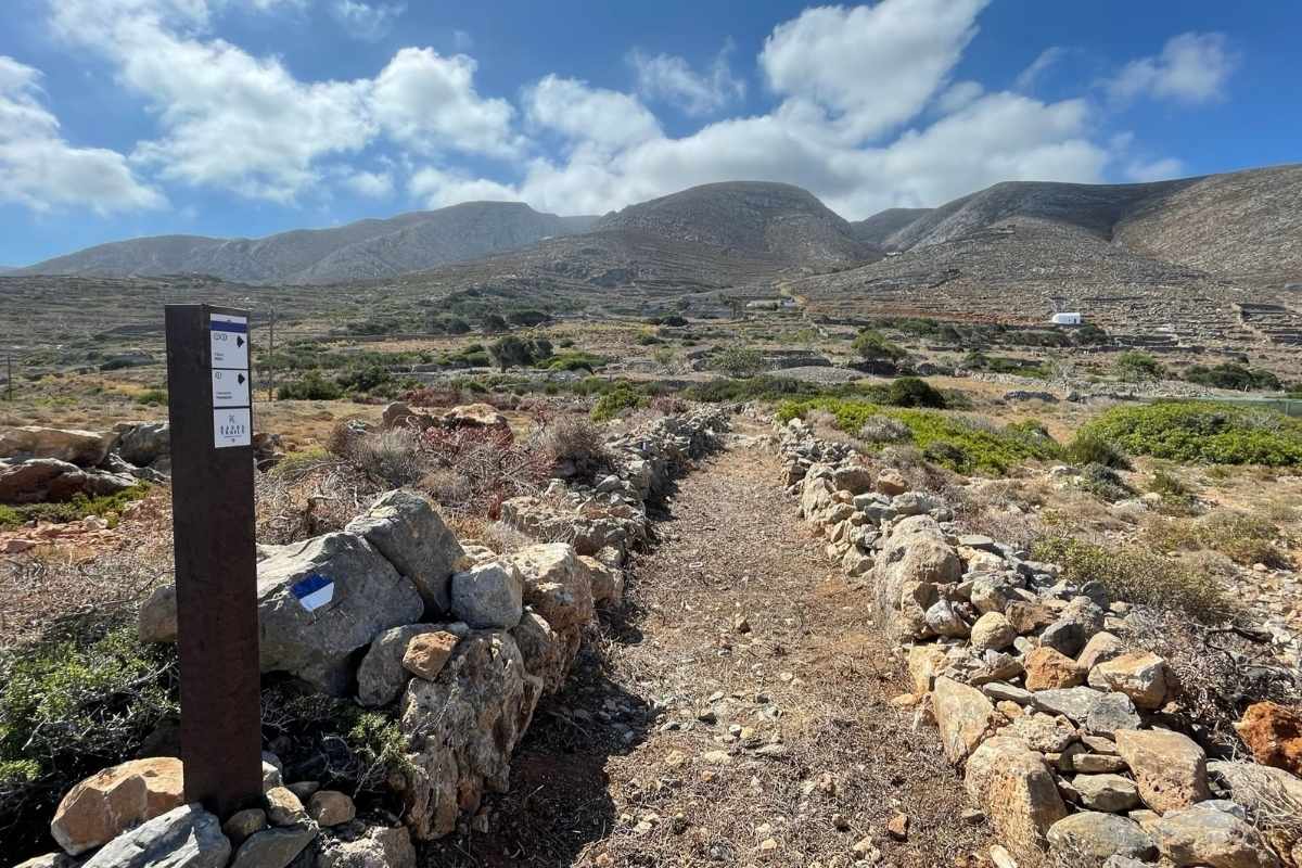 Directional trail sign with trail on Kasos A recycled plastic directional trail sign with an old stone trail at the background on the island of Kasos