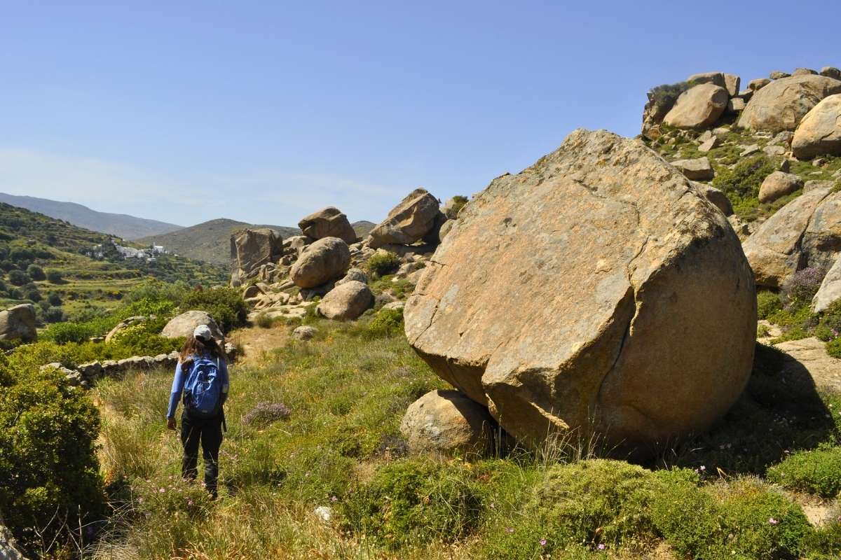 A person hiking on a trail around boulders at Tinos, Volax
