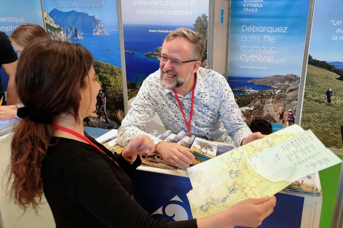 A person with a hiking map promoting trails at a fair in France