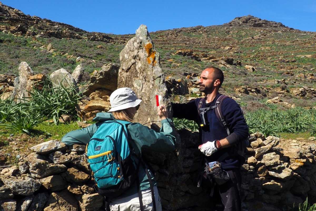 Two people way-marking a trail with paint signs on the island of Tinos, Greece
